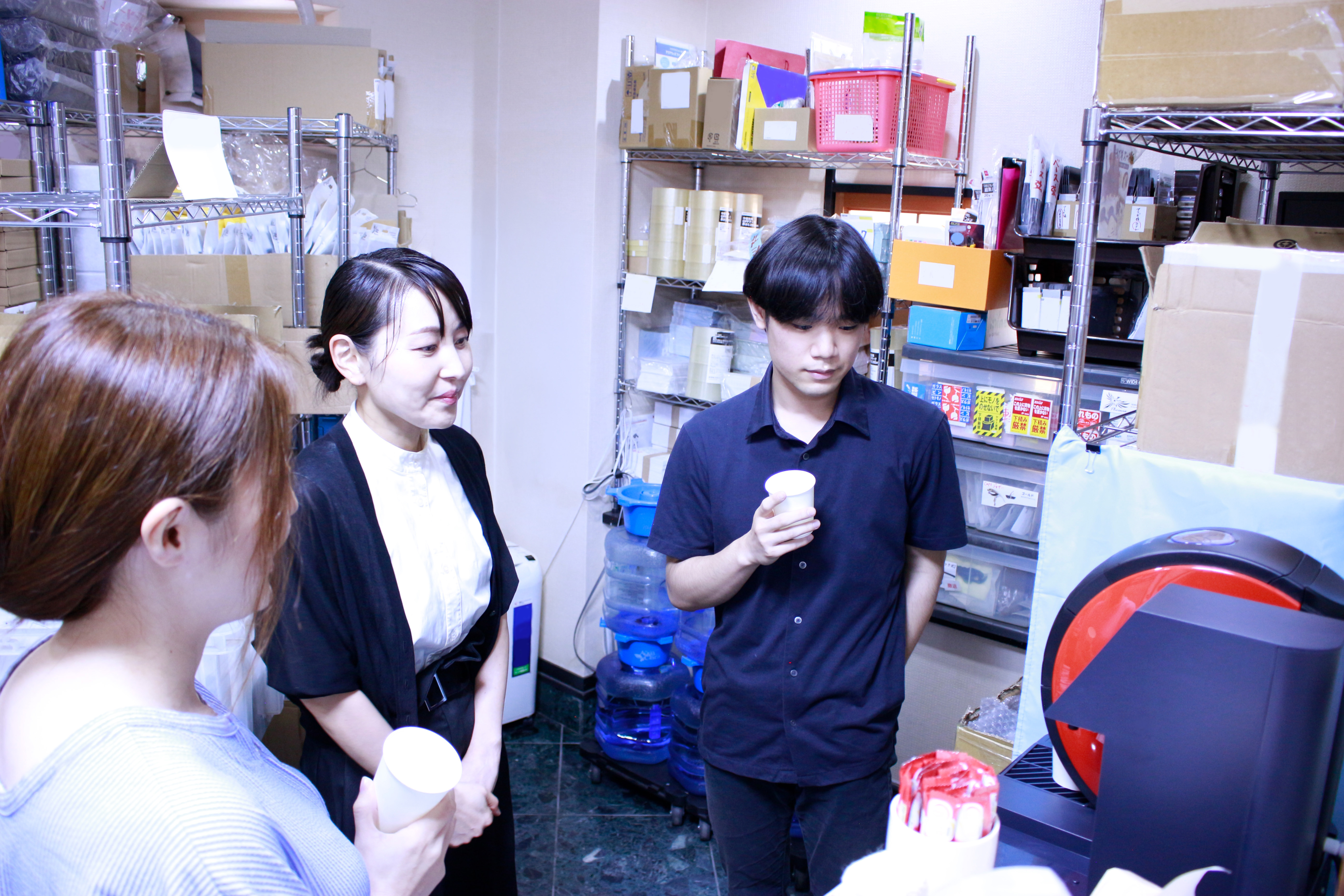 備品棚の前でスタッフが会話する様子